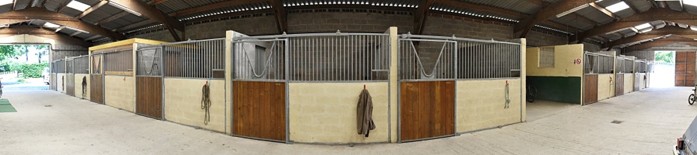 Écurie couverte de la ferme, avec ses boxes à chevaux en bois et métal